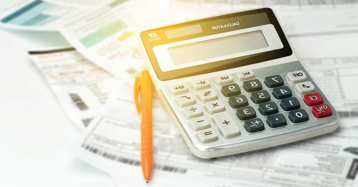 Calculator with pen sitting on stack of forms